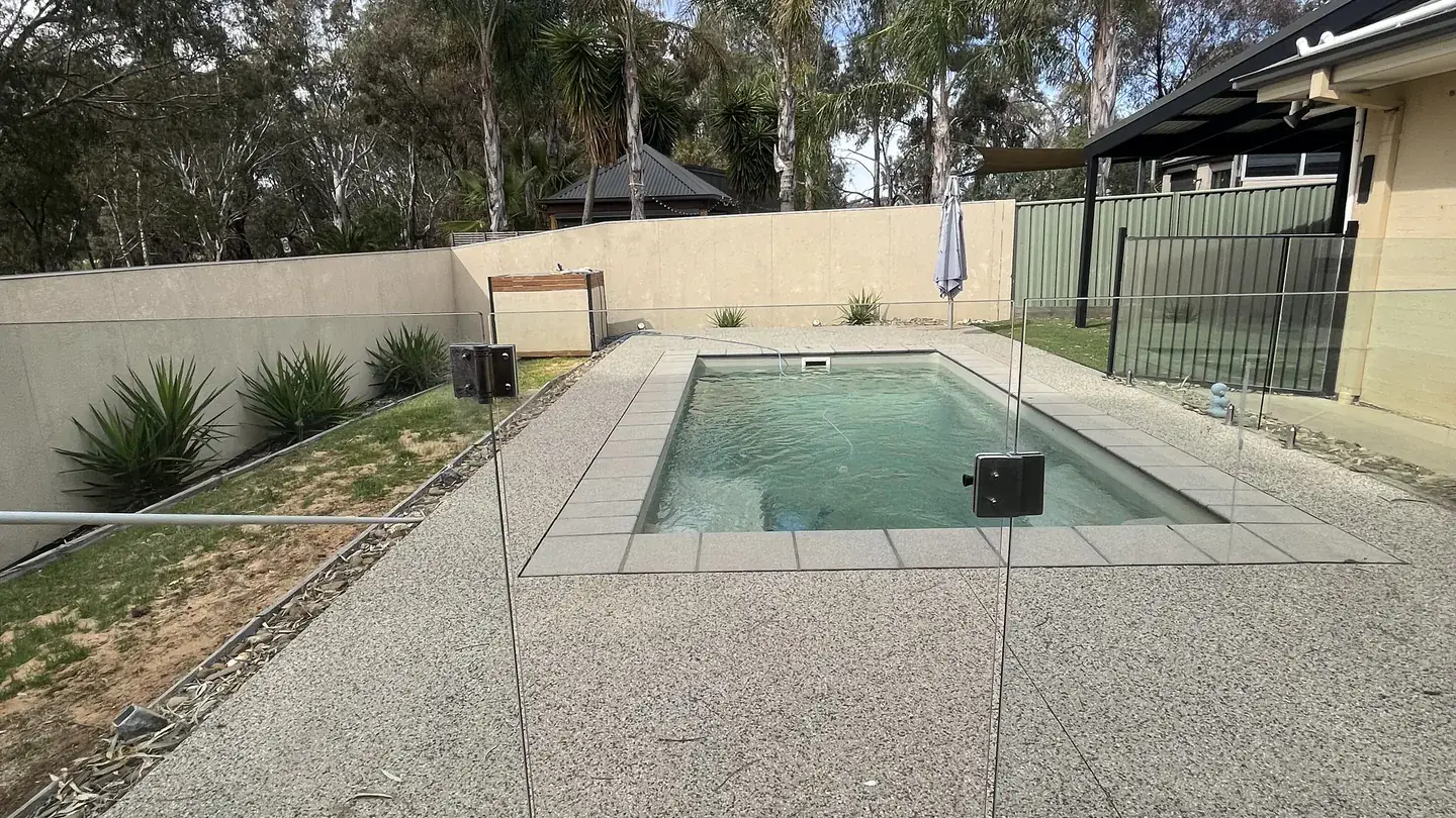 A lap pool and spa with a paved surround in a landscaped backyard