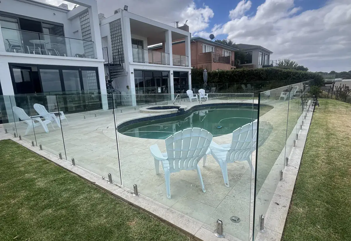A spa and pool behind a frameless glass safety fence at a modern home
